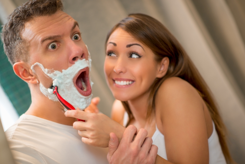 Cheerful girl shaving her boyfriend. 