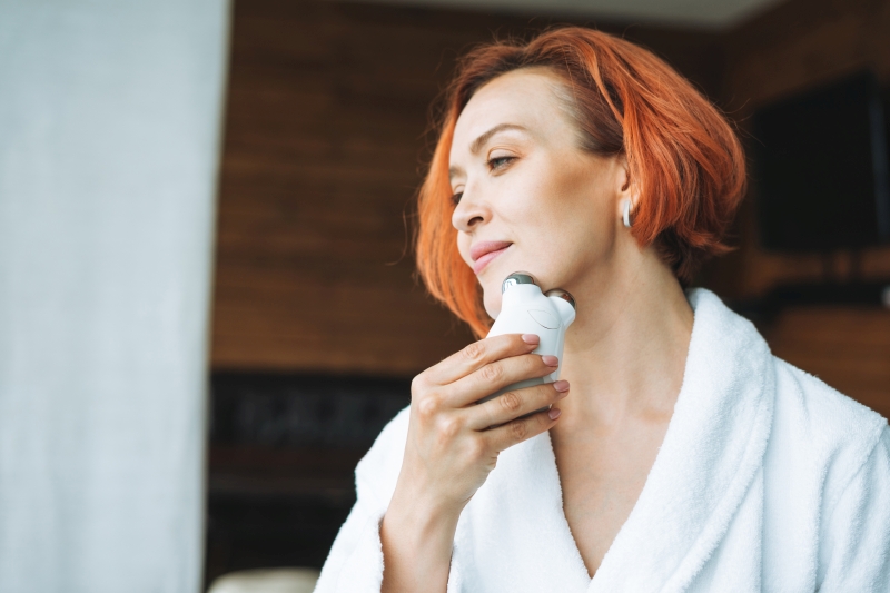 smiling woman with microcurrent facial massager 