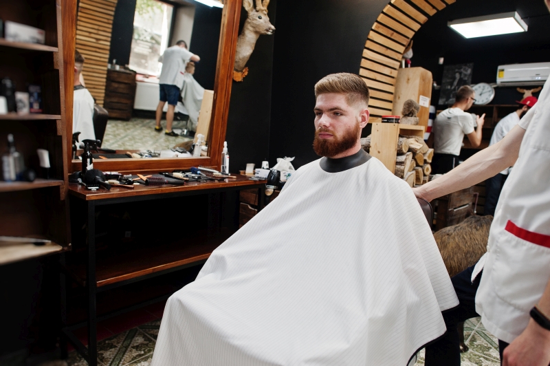 Young bearded man getting haircut 