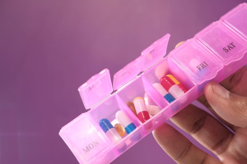 man hand holding pill box on color background